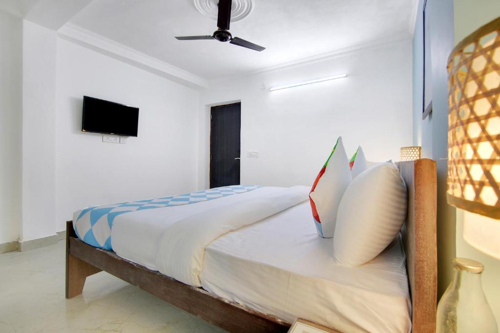 a bedroom with a bed with pillows and a tv at Flagship Khanpur STAY in New Delhi