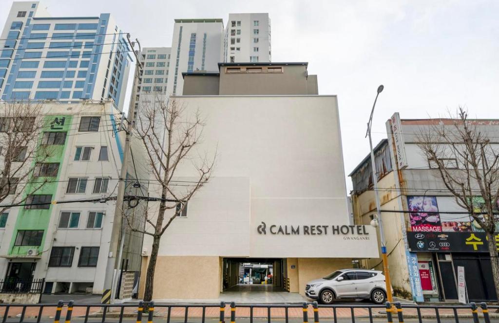 釜山にあるGwanganli Calm Rest Hotelの建物横の商店街前に停車する車