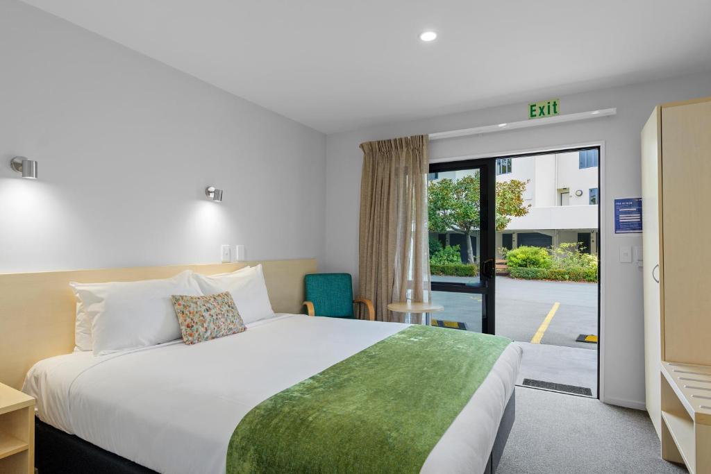 ein Hotelzimmer mit einem Bett und einer Glasschiebetür in der Unterkunft Bella Vista Motel & Apartments Christchurch in Christchurch