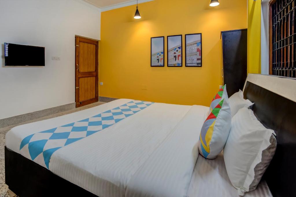 a bedroom with a large bed and a yellow wall at OYO Home Jaam's Home Stay in Bhubaneshwar