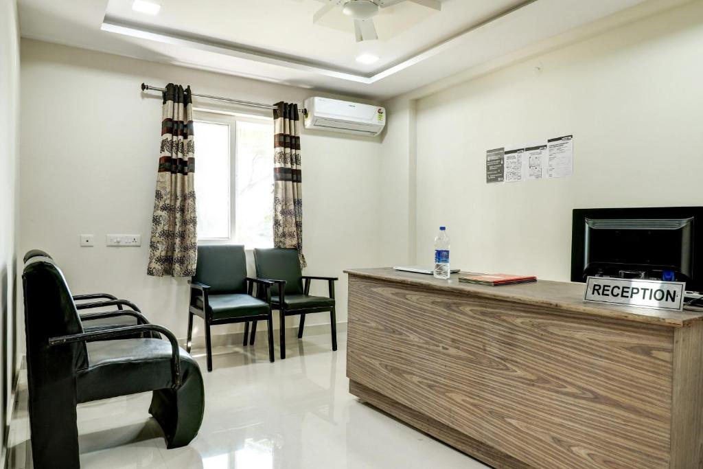 a living room with a tv and chairs and a desk at Super Capital O Vrisha Inn in Jalāripeta