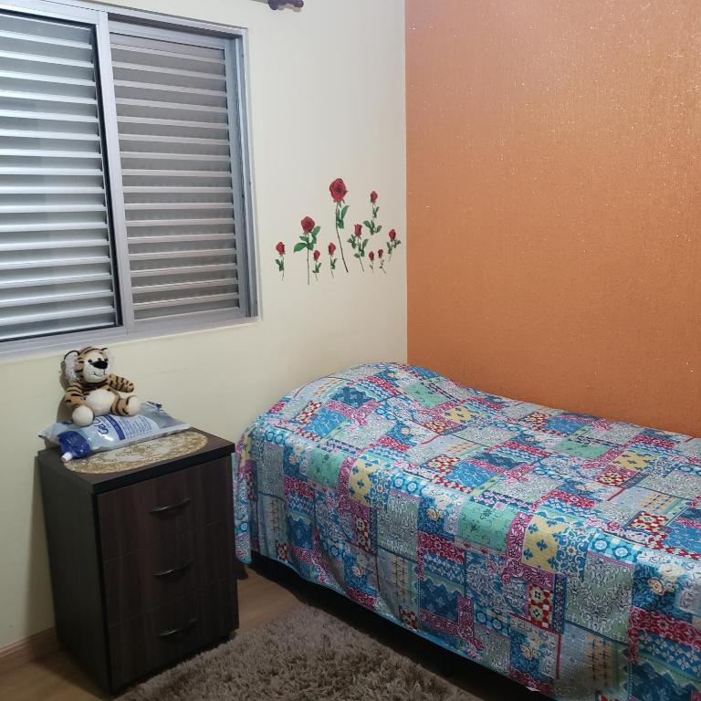a bedroom with a bed and a table with a teddy bear at Meu Cantinho in Campinas