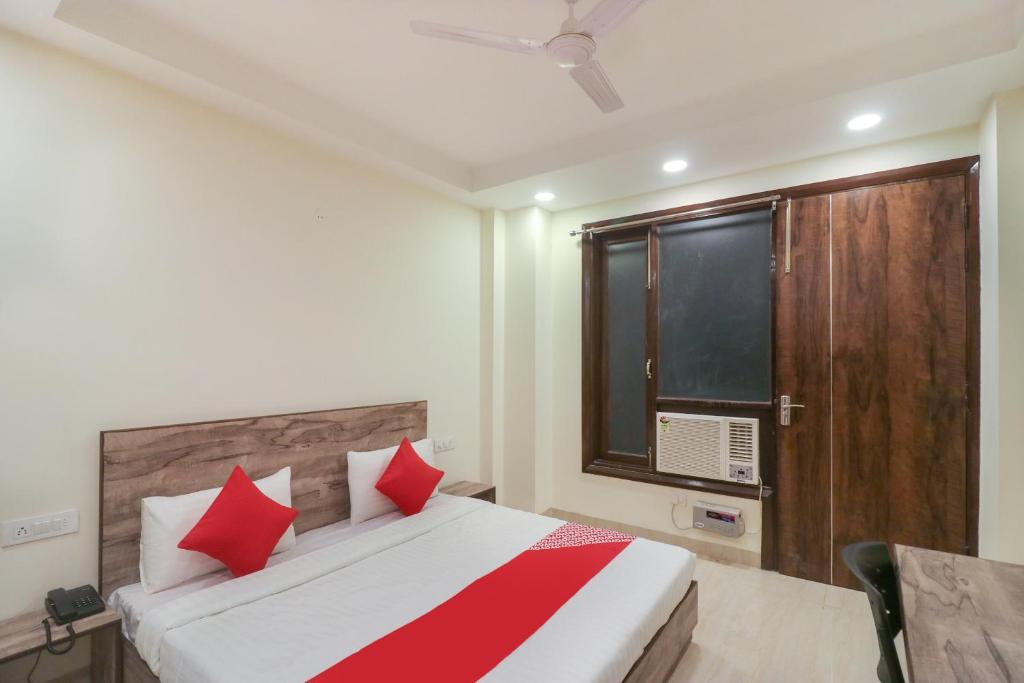 a bedroom with a bed with red pillows and a window at Flagship Comfort Residency Near Artemis Hospital in Gurgaon