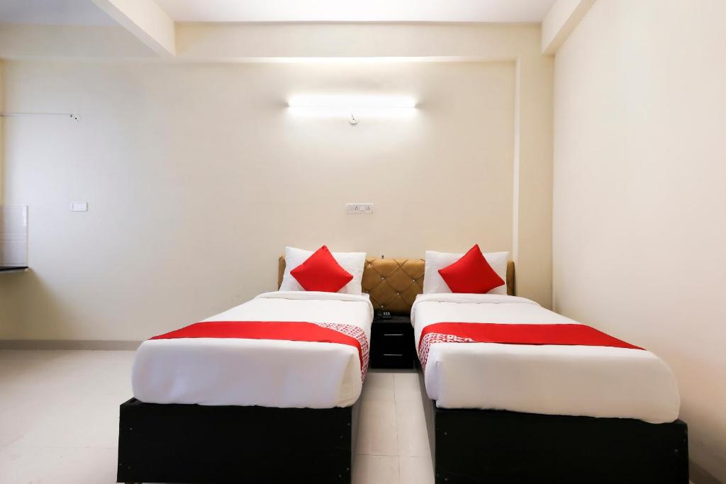 Hotel Aashirwad في إندوري: سريرين في غرفة مع وسائد حمراء