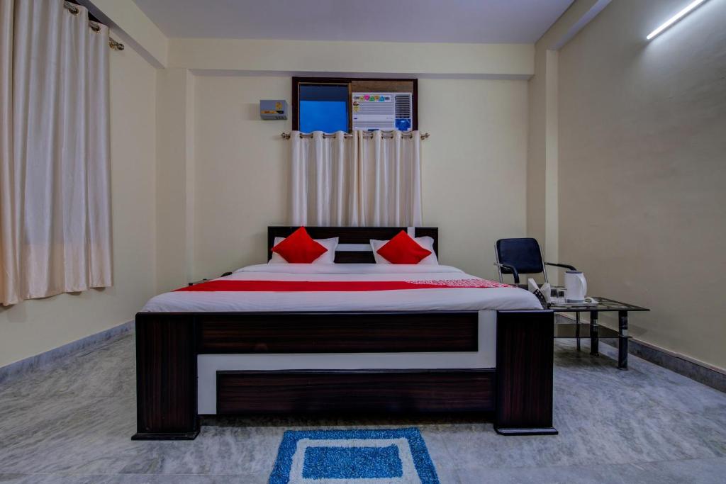 1 dormitorio con 1 cama grande con almohadas rojas en Super OYO Flagship Rajbanshi Nagar en Patna