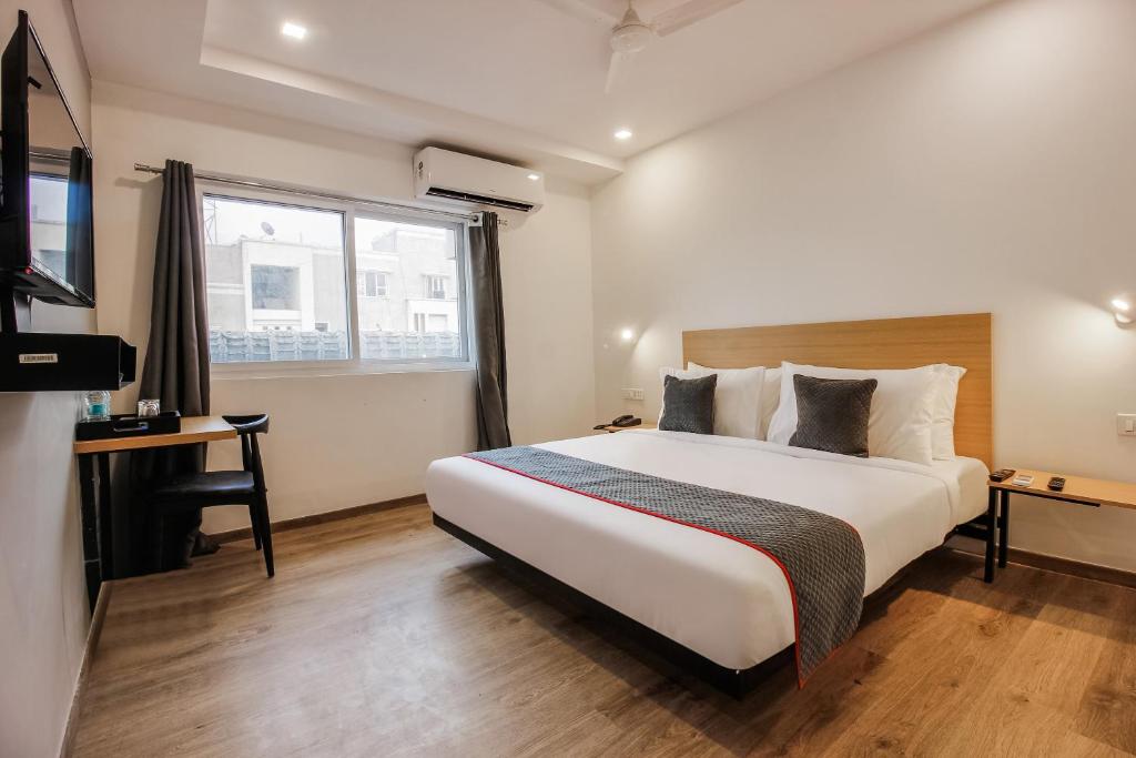 a bedroom with a bed and a desk and a television at Townhouse Begumpet Near Hyderabad Central in Ameerpet