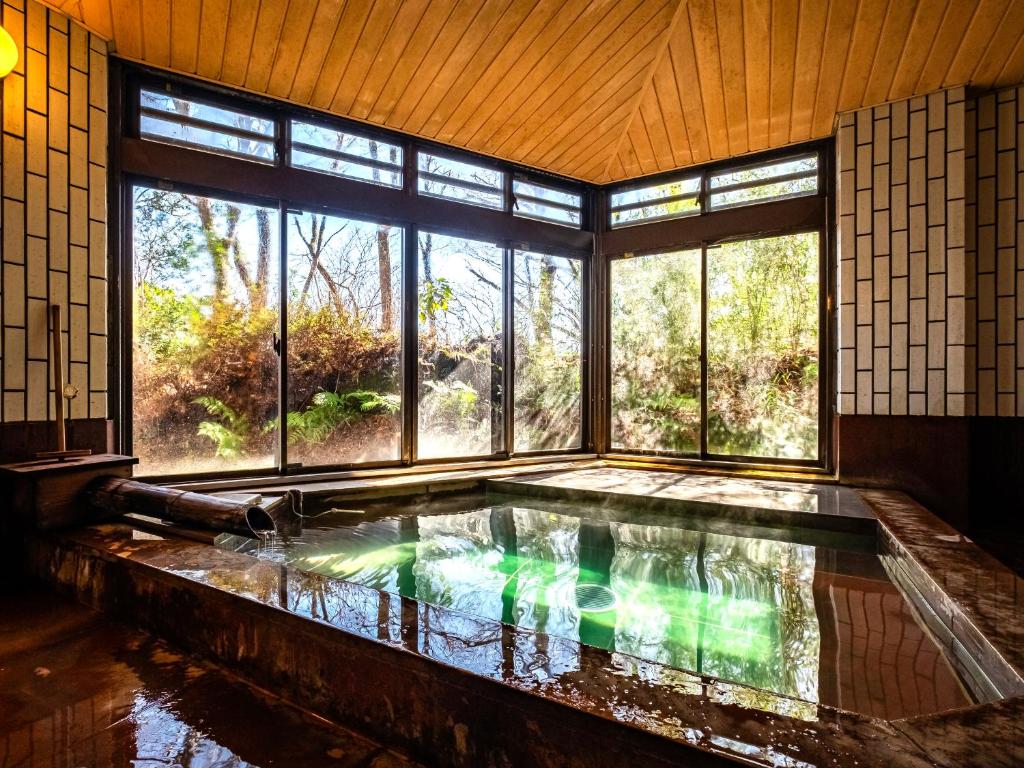 a bath tub in a room with a large window at HAKONE GORA ONSEN Hotel Kasansui in Hakone
