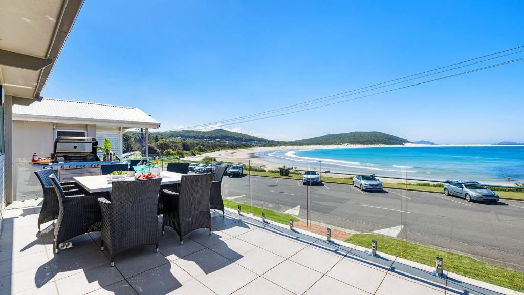 a balcony with a table and chairs and a view of a beach at On the Beach in Fingal Bay