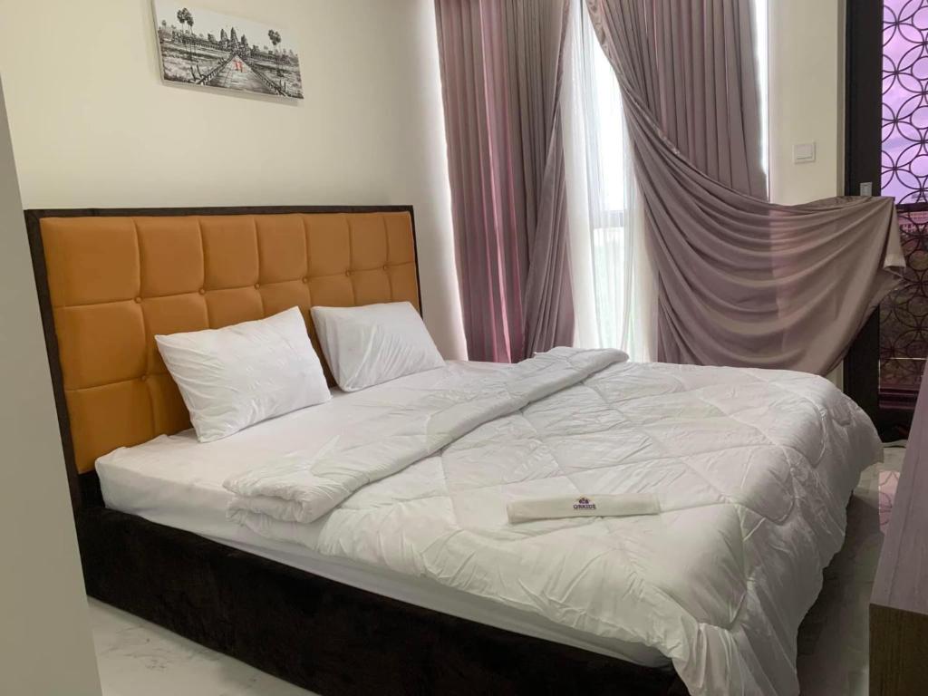 Una cama en un dormitorio con una bata. en Orkide Condo en Phnom Penh