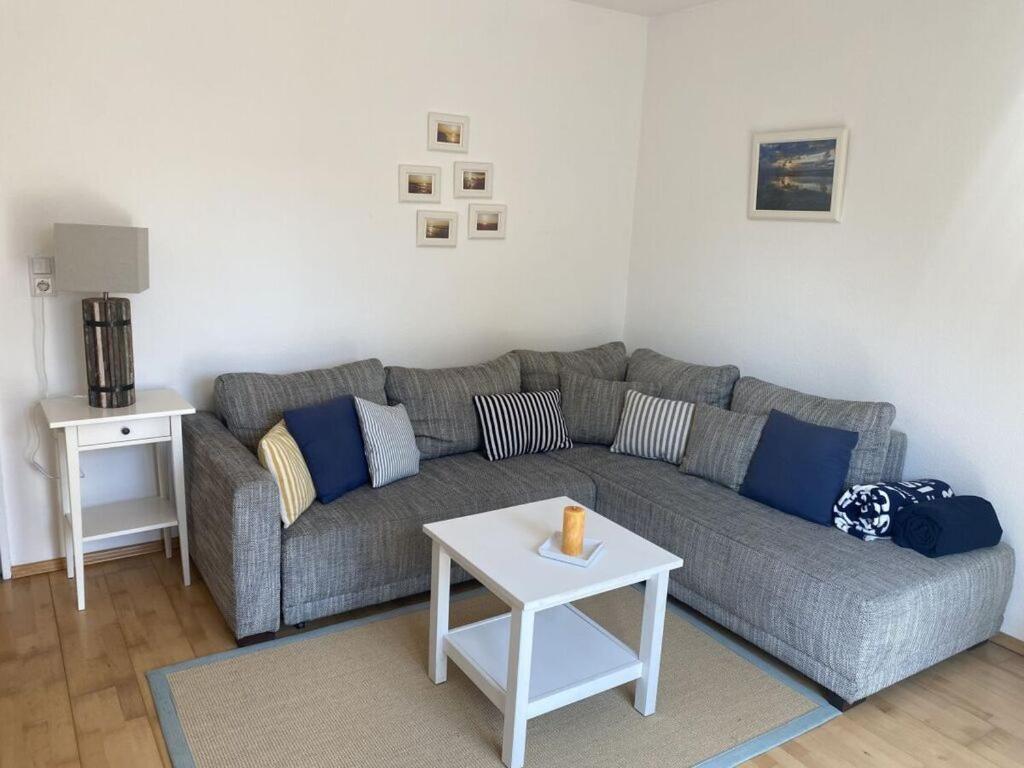 ein Wohnzimmer mit einem grauen Sofa und einem Tisch in der Unterkunft in the Fischer house Lütje Stuv in Juist