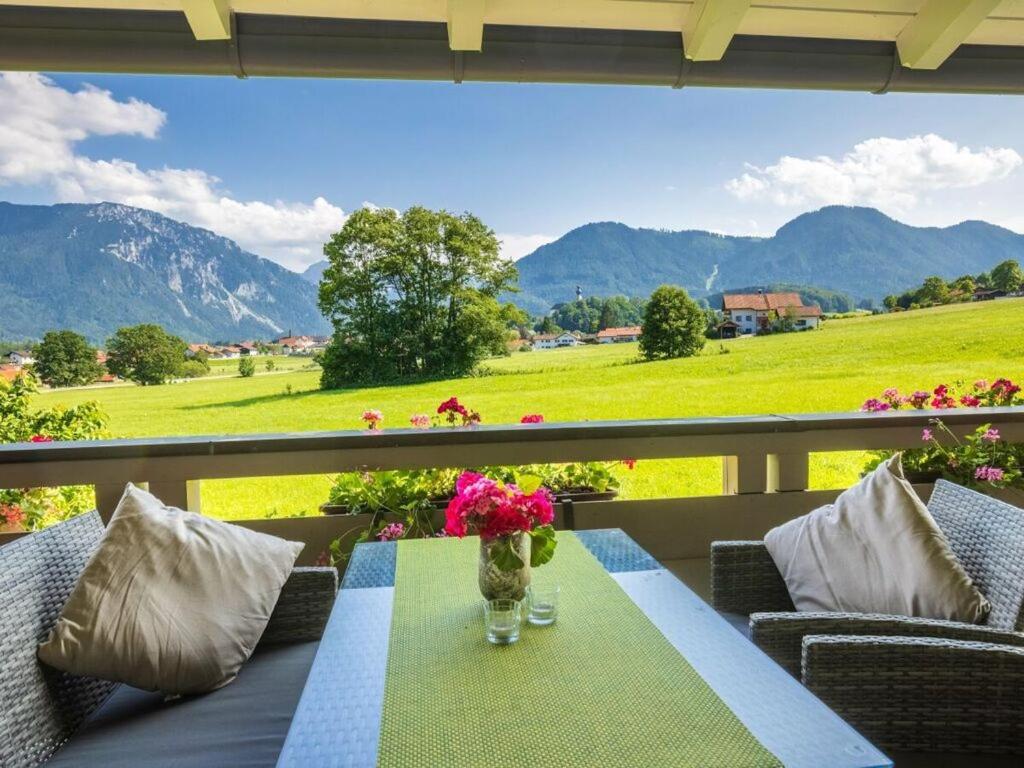 una mesa con un jarrón de flores en el balcón en Hörndlwand Ruhpolding, en Ruhpolding