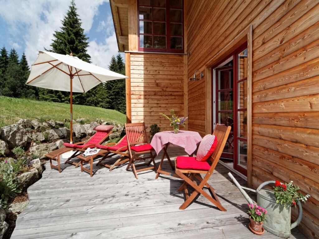 een patio met een tafel en stoelen en een parasol bij Nesterl Modern retreat in Mitterfirmiansreut