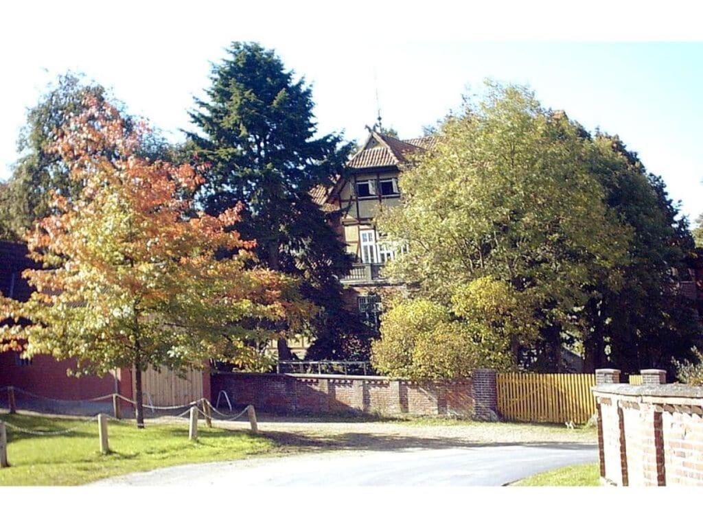 une maison avec une clôture et des arbres devant elle dans l'établissement Heidehof Bunge Modern retreat, à Uelzen