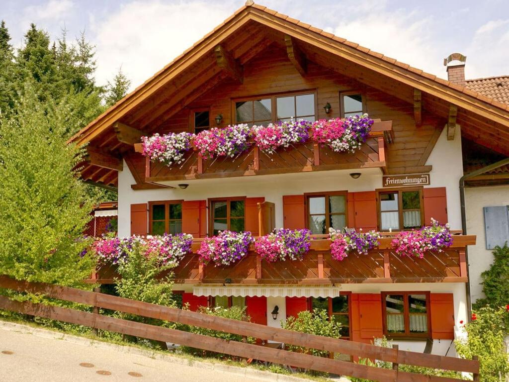 ein Holzhaus mit Blumen auf dem Balkon in der Unterkunft Bader Modern retreat in Blaichach