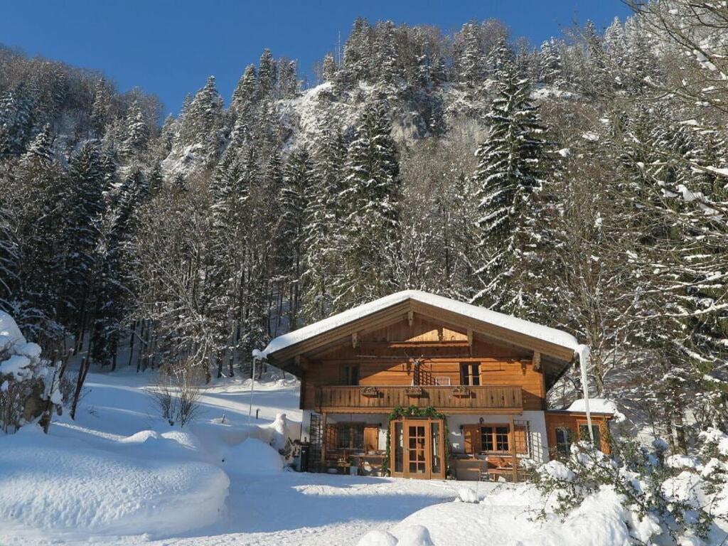 eine Blockhütte im Schnee mit schneebedeckten Bäumen in der Unterkunft Waterval in het huis Boshoek in Aschau im Chiemgau