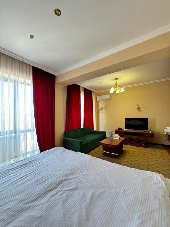 een hotelkamer met een bed, een bank en een televisie bij Luxurious in Taraz