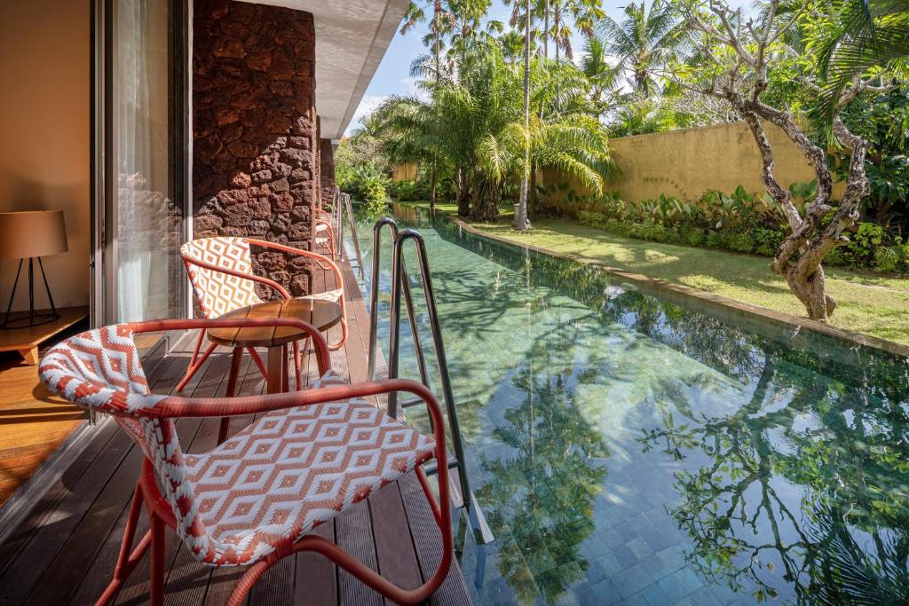 a porch with two chairs and a swimming pool at MERUSAKA Nusa Dua in Nusa Dua