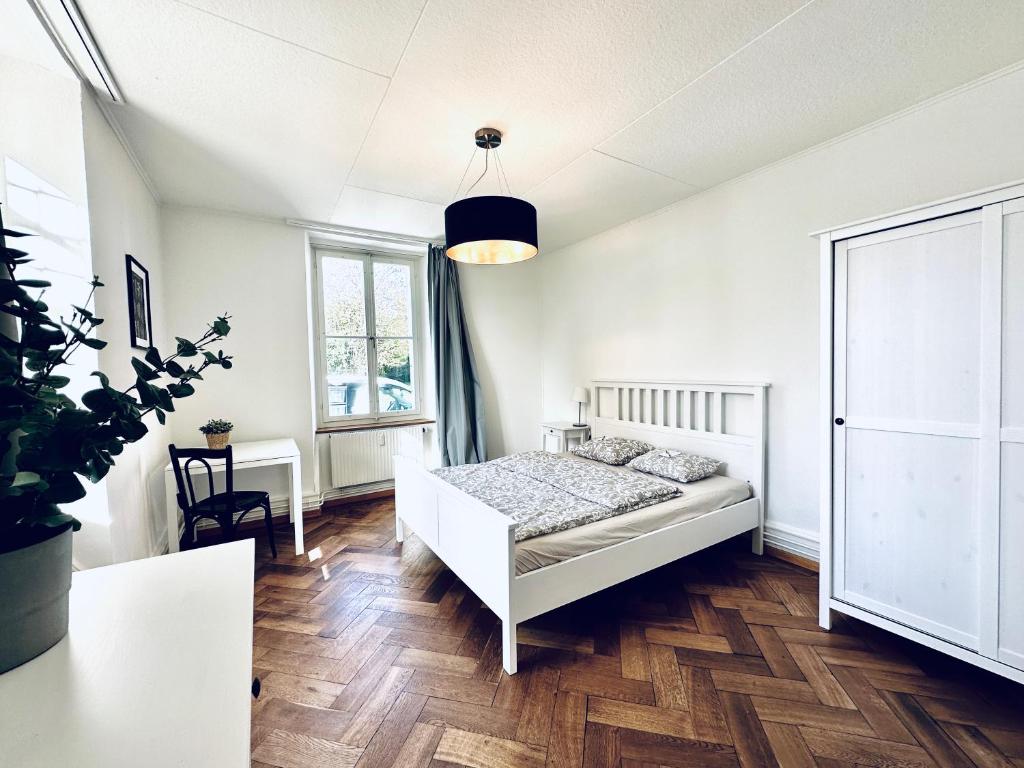 a white bedroom with a bed and a table at Business Apartment in Derendingen in Derendingen