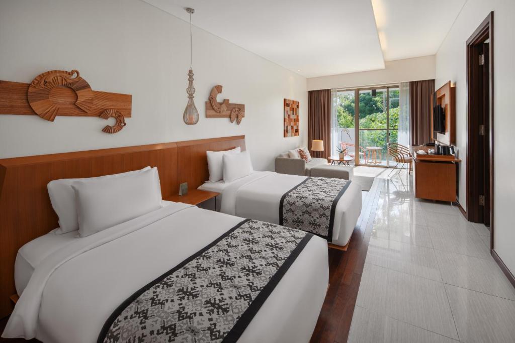 a hotel room with two beds and a living room at MERUSAKA Nusa Dua in Nusa Dua