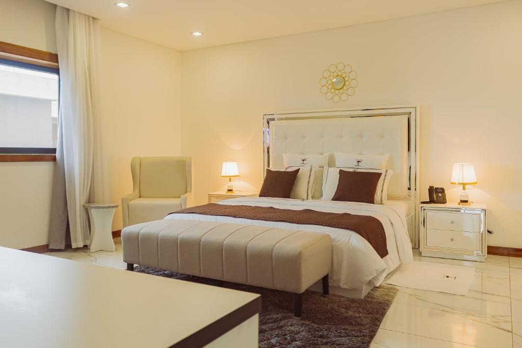 a bedroom with a large bed and a chair at Hotel Estoril in Beira