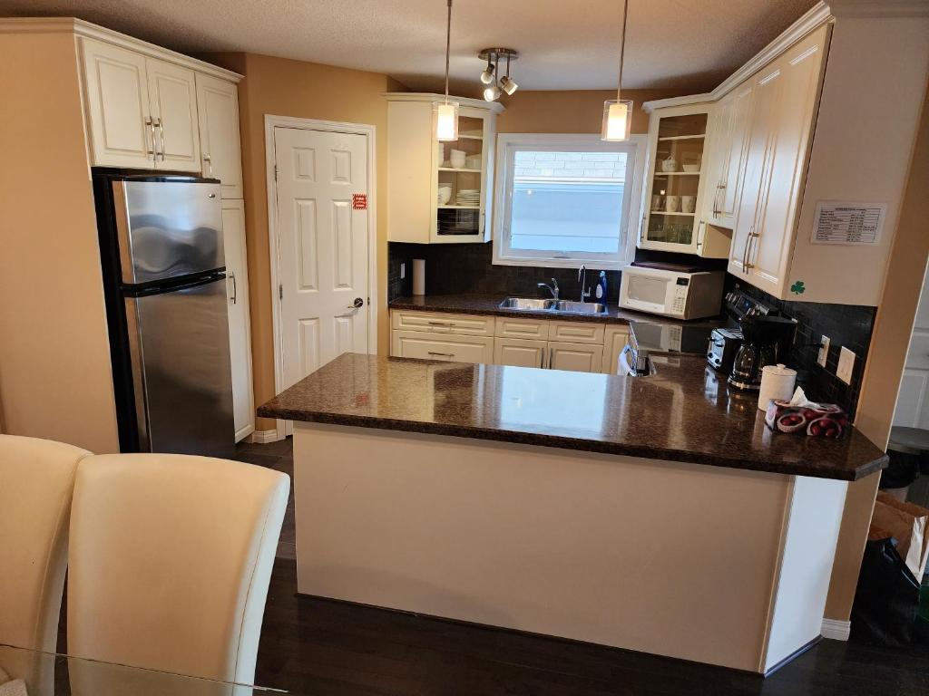 een keuken met witte kasten en een zwarte koelkast bij Beautiful updated home centrally located, close to General Hospital in Regina