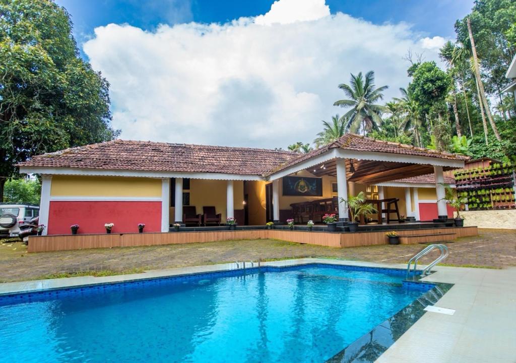 a villa with a swimming pool in front of a house at Chandragiri Wayanad Traditional Bungalow by VOYE HOMES in Vaduvanchal