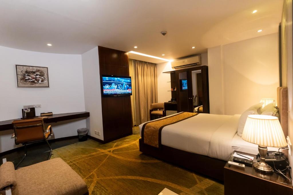 Habitación de hotel con cama, escritorio y TV. en Hotel Bengal Canary Park, en Dhaka