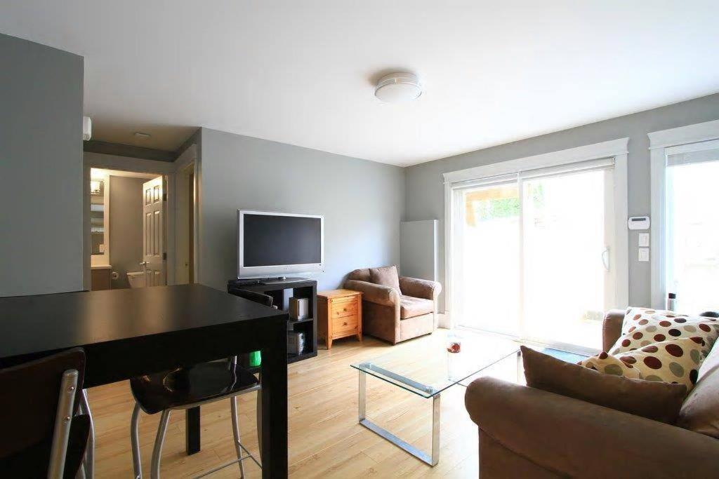 溫哥華的住宿－QE Park Garden suite 3BR 1.5Ba，客厅配有桌子、沙发和电视