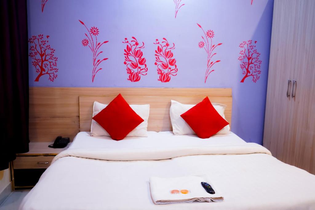 a bedroom with a large bed with red pillows at Roomshala 002 Rose Residency Near Yashobhoomi in New Delhi