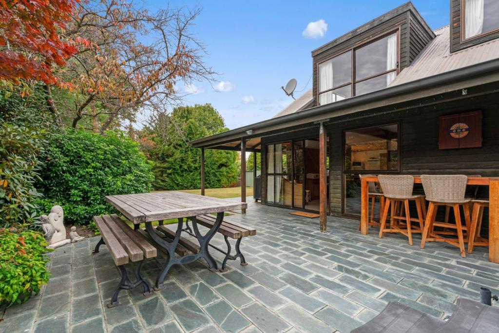 a patio with a wooden picnic table and chairs at So Good On Sargood - Wanaka Holiday Home in Wanaka