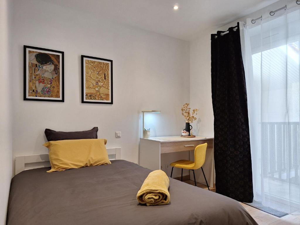 a bedroom with a bed and a desk and a window at Chambre GUSTAV in Agen