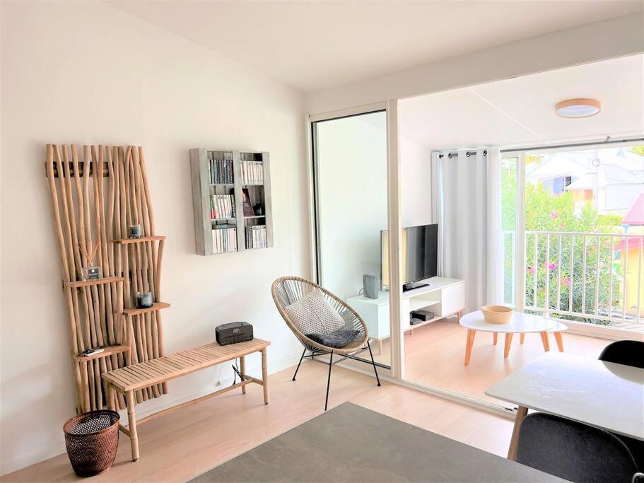 ein Wohnzimmer mit einem Stuhl und einem Tisch in der Unterkunft Appt Cambria - à 2 min du Lagon de la Saline-les-bains in Saint-Paul