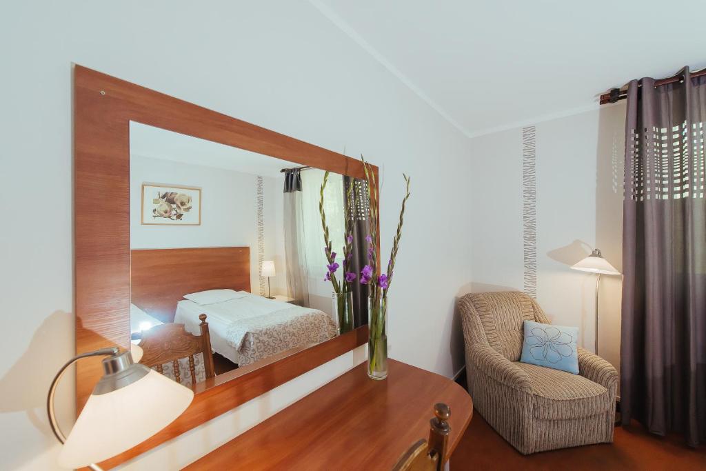 Habitación con espejo, silla y cama en Hotel Pod Sosnami, en Osieck