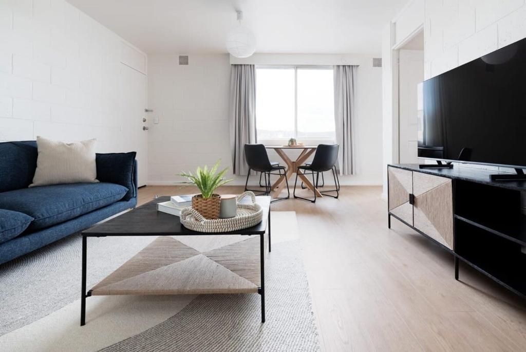 Una sala de estar con un sofá azul y una mesa. en Parkside Apartment Near CBD & City Park with Parking, en Launceston