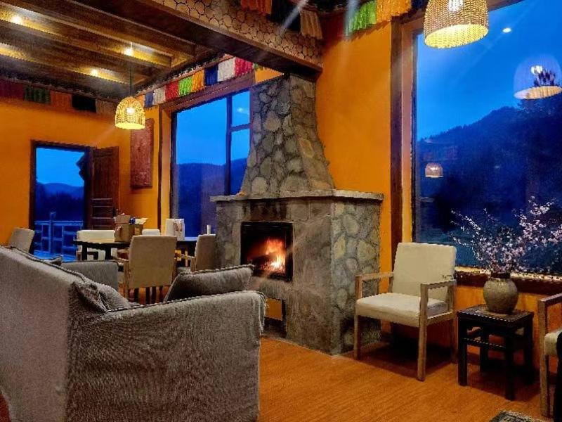 a living room with a stone fireplace and chairs at 九寨沟阿布氇孜民宿Jiuzhaigou Valley Abluzi B&B in Jiuzhaigou