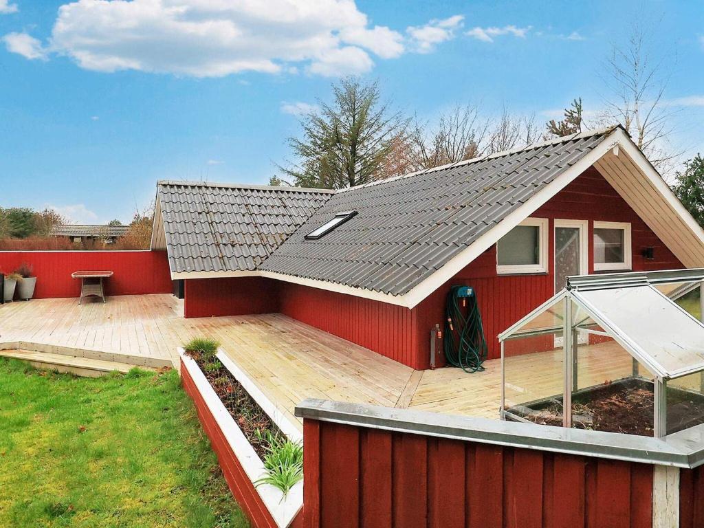 ein rotes Haus mit einer Terrasse und einem Dach in der Unterkunft Holiday home Hals LXXIII in Hals