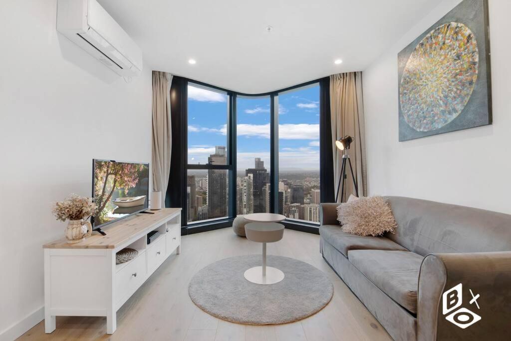 a living room with a couch and a large window at Rest Highrise City View Apt Melbourne Central in Melbourne