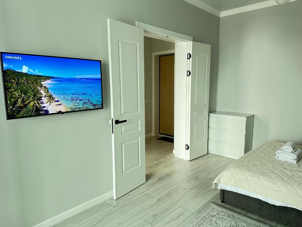een slaapkamer met een flatscreen-tv aan de muur bij Esil Riverside Elite Apartments in Astana