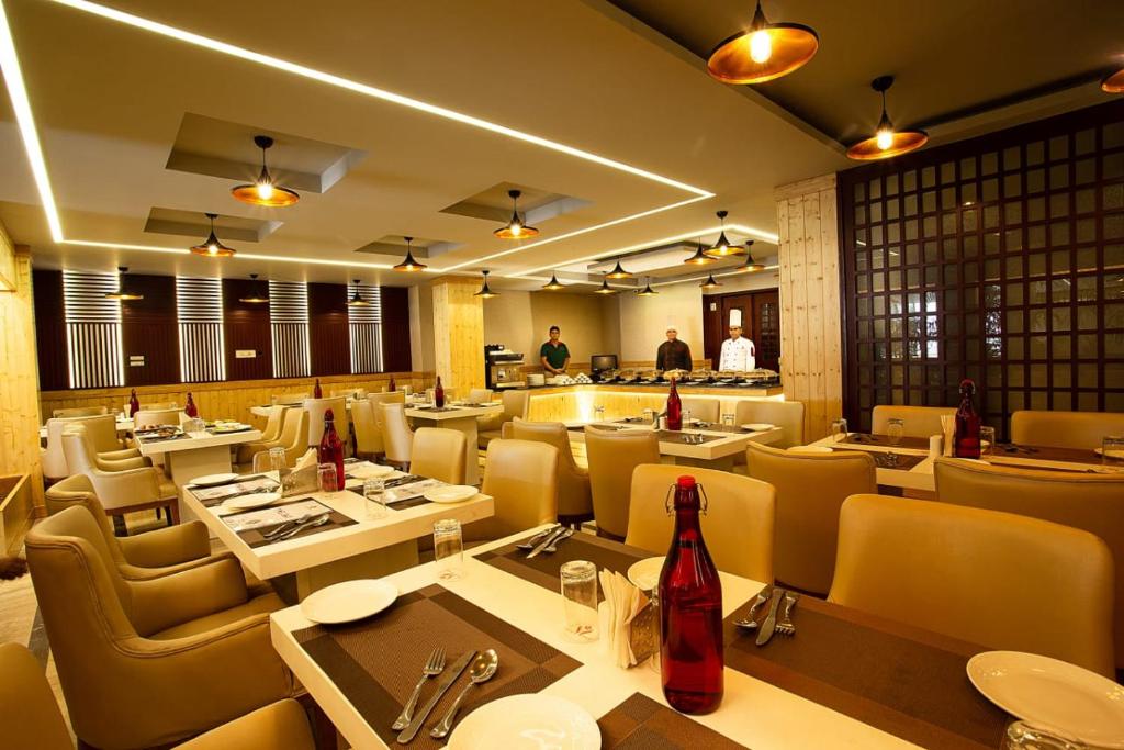 un restaurante con mesas y sillas y gente de fondo en Airport hotel deep palace near international airport, en Nueva Delhi