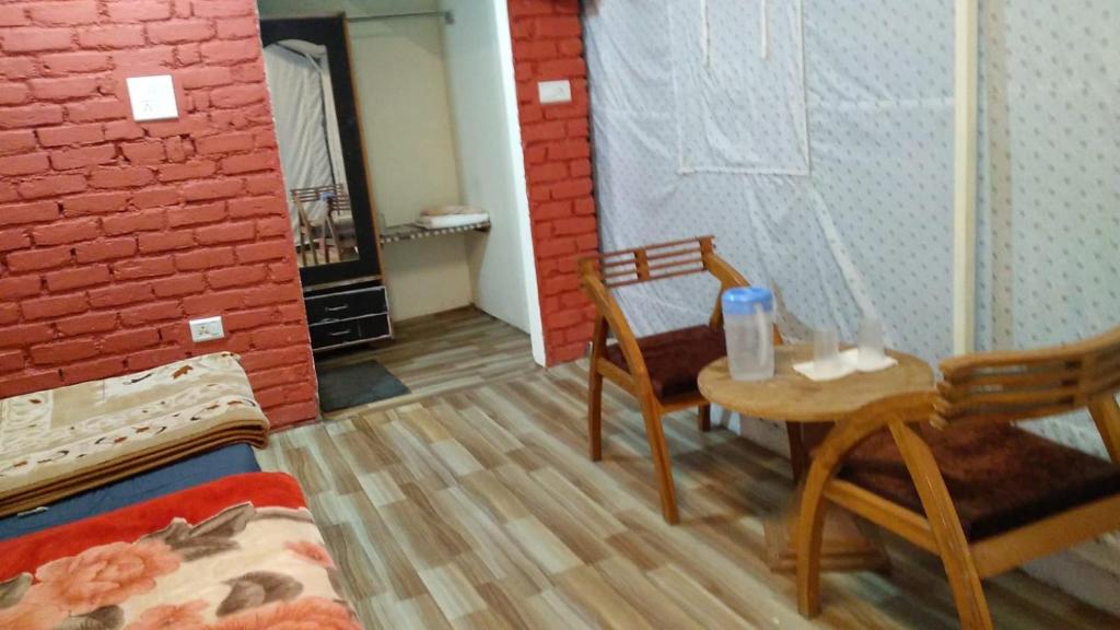Zimmer mit 2 Stühlen und einem Tisch in einem Zimmer in der Unterkunft Kandi Orchard Resort in Masuri