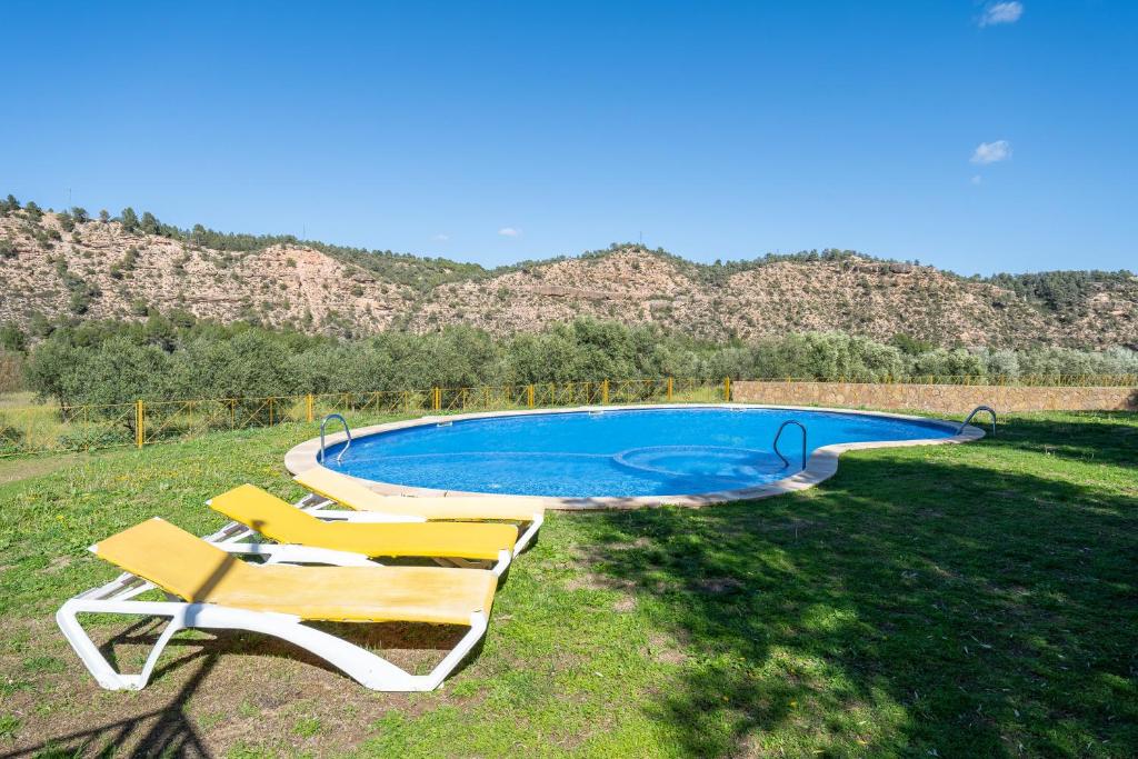 una piscina con sillas y montañas en el fondo en Mas de Sisco, en Flix