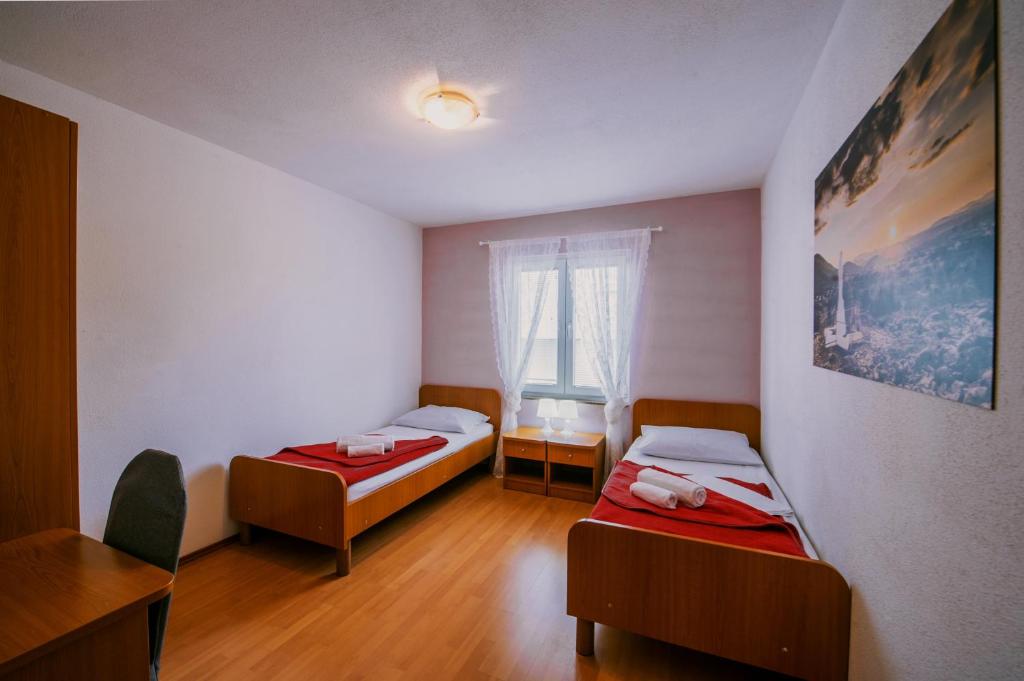 Zimmer mit 2 Betten, einem Tisch und einem Fenster in der Unterkunft Villa Marinko in Međugorje