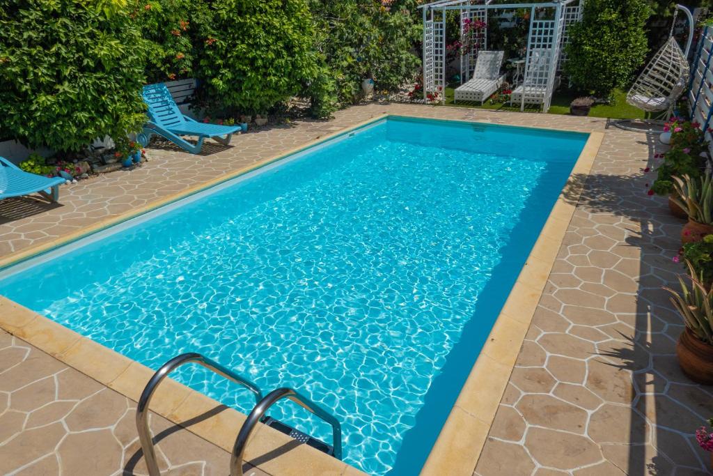 a swimming pool with blue water in a yard at Greek Island Style 2 bedroom Villa with Pool next to the Sea in Larnaka