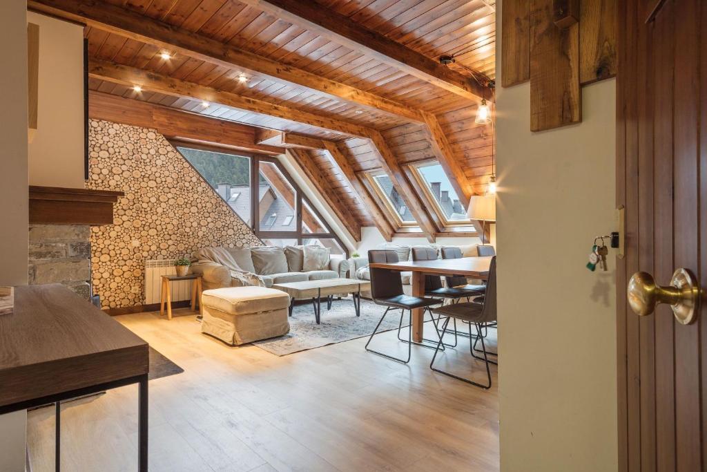 a living room with wooden ceilings and a table and chairs at Luderna - Dúplex Val de Ruda C10 Estanh Redond in Baqueira-Beret