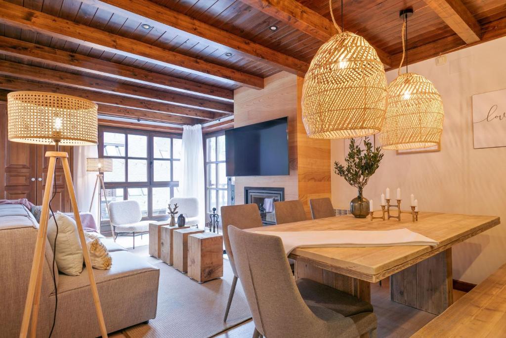 a dining room with a table and chairs and two lights at Luderna - Apartamento Val de Ruda B3 Entecada in Baqueira-Beret