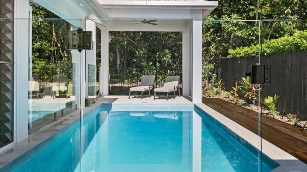 a swimming pool with a patio and a house at Coastal Vibes - Palm Cove in Palm Cove