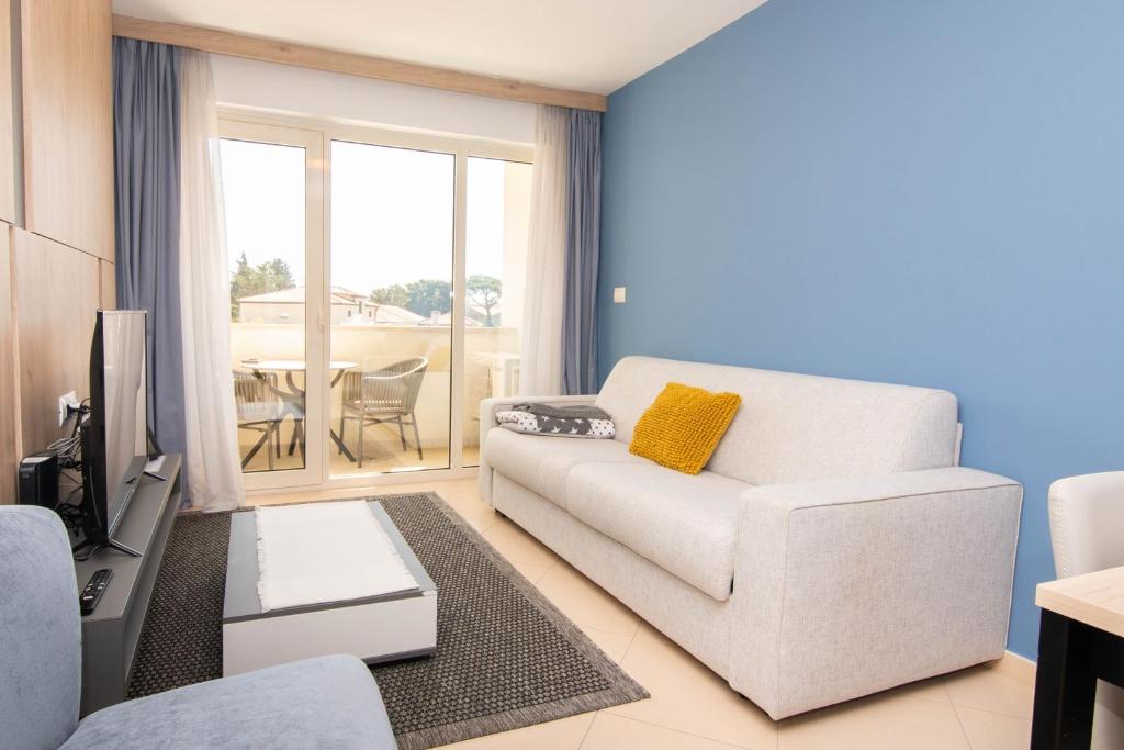a living room with a white couch and a television at Pet Friendly Apartment Blue Ocean Umag in Umag