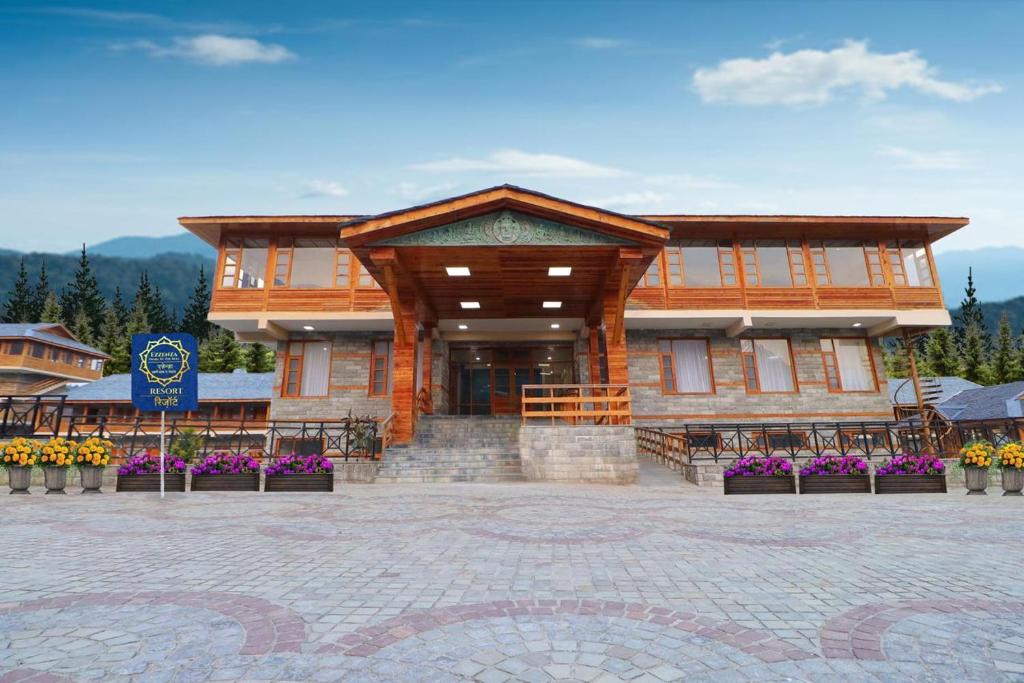 a large wooden building with flowers in front of it at Ezzenza Swarg by Beas Golf Resort - Devlok Manali in Baragrān