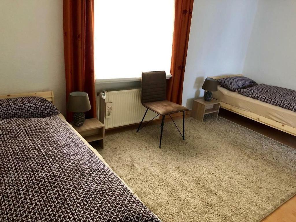 1 dormitorio con 2 camas, silla y ventana en Zimmer in Kyritz, en Kyritz
