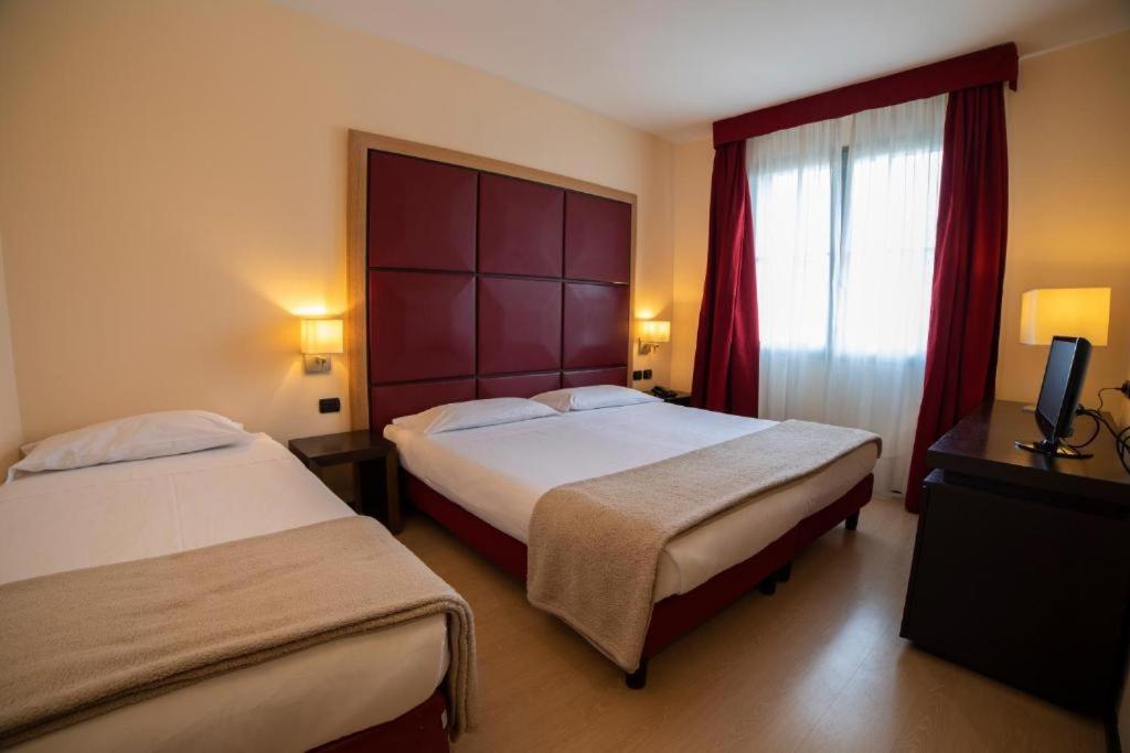 a hotel room with two beds and a window at ALBA HOTEL in Reggio Emilia